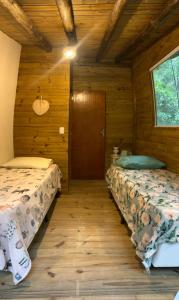 a bedroom with two beds in a wooden cabin at Chalé Shangri-la in Paraty