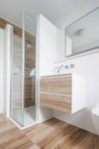 een witte badkamer met een douche en een wastafel bij Appartementen de Strandloper in Bergen aan Zee +85 foto's