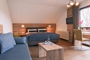a bedroom with a bed and a couch and a table at Restaurant & Landhotel Winter in Gomadingen +36 photos