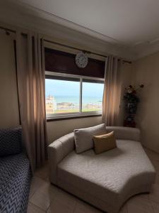 a couch sitting in front of a window with a clock at Entire Ocean-View Apartment in Rabat