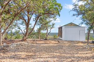 a small white building in the middle of trees at Daybreak Ridge Sunrise Bluff in Blanco +19 photos