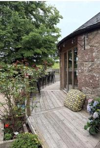 a wooden deck with a table and chairs on it at Lodge at Lochside in Bridgend of Lintrathen
