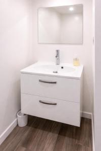 a white bathroom with a sink and a mirror at Petit cocon moderne Cuisine équipée TV WIFI in Roubaix