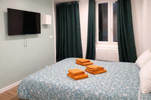 two orange towels sitting on top of a bed at Petit cocon moderne Cuisine équipée TV WIFI in Roubaix