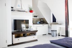 a kitchen with white cabinets and a flat screen tv at Altstadtloft am Kaulberg in Bamberg