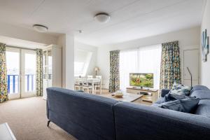 een woonkamer met een blauwe bank en een tafel bij Appartementen de Strandloper in Bergen aan Zee