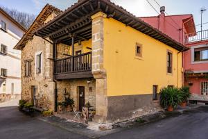 a yellow building with a balcony on a street at Casa Rural Moradiellos-Cabrales Axtur 4 personas con vistas in Arenas de Cabrales