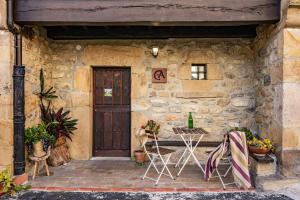 a stone building with two chairs and a door at Casa Rural Moradiellos-Cabrales Axtur 4 personas con vistas in Arenas de Cabrales