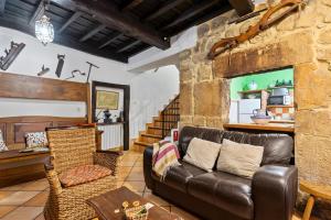 a living room with a leather couch and a table at Casa Rural Moradiellos-Cabrales Axtur 4 personas con vistas in Arenas de Cabrales
