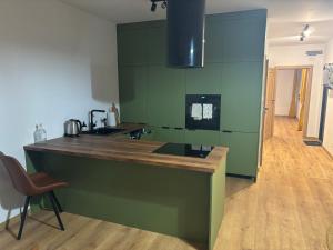 a kitchen with green walls and a wooden counter top at Apartament Przy Parku in Bełchatów