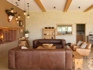 a living room with a brown leather couch at Stroomrivier Lodge in Boshoek