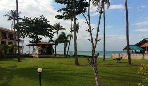 a yard with palm trees and a building and the ocean at Aloha Lanta in Ko Lanta