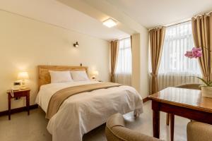 a hotel room with a bed and a desk and a bed sidx sidx sidx sidx at Hotel Cipriani in Tarma