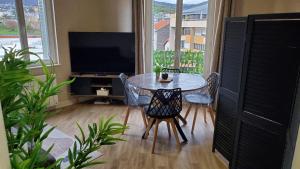 a dining room with a table and chairs and a television at Charmant T2 Spacieux idéalement situé - 2 chambres in Clermont-Ferrand