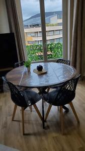 a table and chairs in a room with a large window at Charmant T2 Spacieux idéalement situé - 2 chambres in Clermont-Ferrand +10 photos