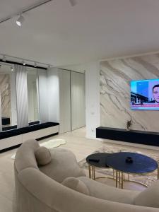 a living room with a couch and a tv on a wall at Luxury Promenada Craiova in Craiova