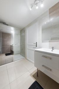 a white bathroom with a sink and a shower at Les Remparts du Loing in Moret-sur-Loing