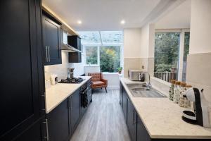 a kitchen with black cabinets and a large window at HollyTree - Family and Business Stay with parking in Cambridge