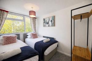 two beds in a room with a window at HollyTree - Family and Business Stay with parking in Cambridge