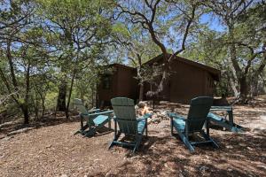 a group of chairs and a table in front of a cabin at Lajitas at The Bend in Wimberley