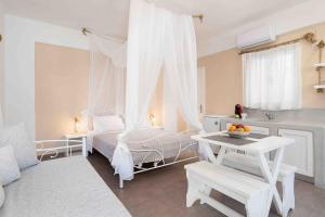 a white bedroom with a bed and a table at Santa Irini 1 in Vourvoúlos