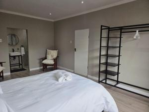 a bedroom with a white bed and a book shelf at Munnik Rest in Polokwane
