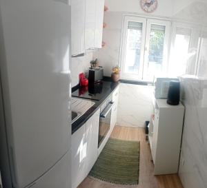 a white kitchen with a stove and a refrigerator at Beach Blue Sesimbra in Sesimbra