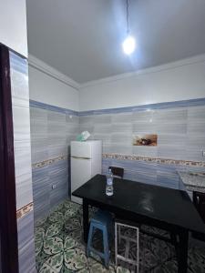 a kitchen with a black table and a refrigerator at Tabriquet urban shared room in Salé