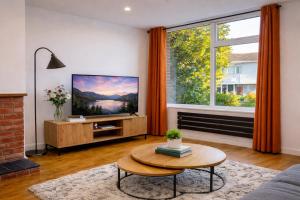 a living room with a tv and a large window at HollyTree - Family and Business Stay with parking in Cambridge