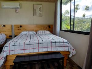 a bedroom with a bed with a plaid blanket and a window at Villa Lago del Sol in El Castillo de La Fortuna