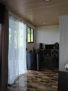 a living room with a white curtain and a kitchen at Villa Lago del Sol in El Castillo de La Fortuna
