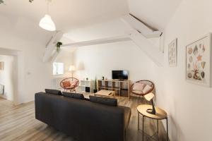 a living room with a black couch and chairs at La porte de Moret in Moret-sur-Loing