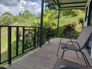 a porch with two chairs and a fence at Villa Lago del Sol in El Castillo de La Fortuna