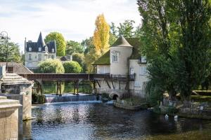 a bridge over a river with a castle in the background at La porte de Moret in Moret-sur-Loing