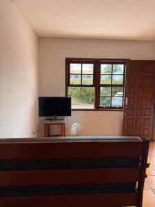 ein leeres Zimmer mit einem Fernseher und einem Fenster in der Unterkunft Prédio Jaque in Garopaba