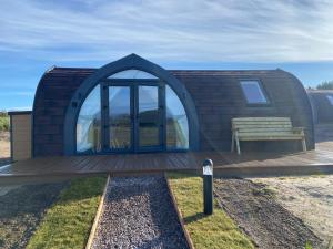 a tiny house with a bench on a deck at Dornoch Pods in Dornoch