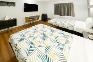 a room with two beds and a table and a television at The Reserve Inn in Salisbury