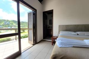 a bedroom with a bed and a large window at Casa Morrinhos 01 in Garopaba