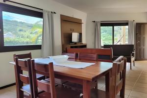 a dining room with a wooden table and chairs at Casa Morrinhos 01 in Garopaba