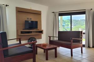 a living room with a chair and a television at Casa Morrinhos 01 in Garopaba