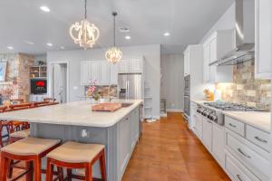 a kitchen with white cabinets and a large island with bar stools at Lakeside Dreamhouse in Canyon Lake +55 photos