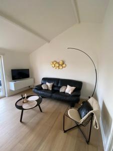 a living room with a black couch and a table at Sea & Stay Bredene Zeewind 2 in Bredene