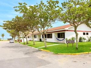 a sign in front of a building with trees at Residencial da Villa in Imbituba