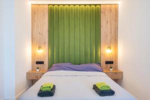 a bedroom with a green wall and a bed with two towels at NXN Airportstay in Cluj-Napoca