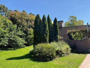 a garden with bushes and trees and a brick building at Suite Republica del Tango Gonnet in Joaquín Gorina