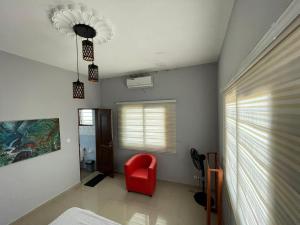 a living room with a red chair and a window at Les Résidences CICA in Ouidah