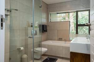 a bathroom with a tub and a toilet and a sink at 23 The Sanctuary Zimbali in Ballito +10 photos