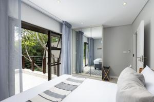 a bedroom with a bed and a large window at 23 The Sanctuary Zimbali in Ballito