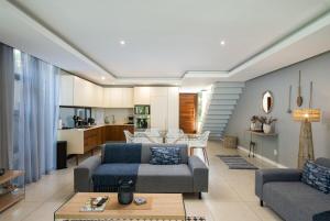 a living room with two couches and a kitchen at 23 The Sanctuary Zimbali in Ballito