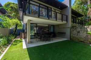 a house with a patio with a table and chairs at 23 The Sanctuary Zimbali in Ballito
